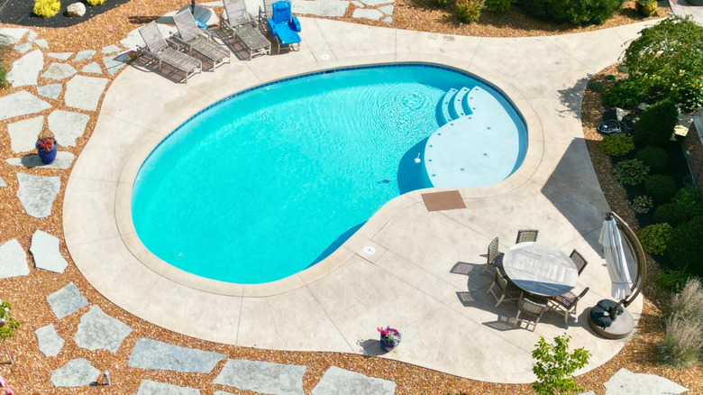 An overhead view of a kidney-shaped swimming pool.