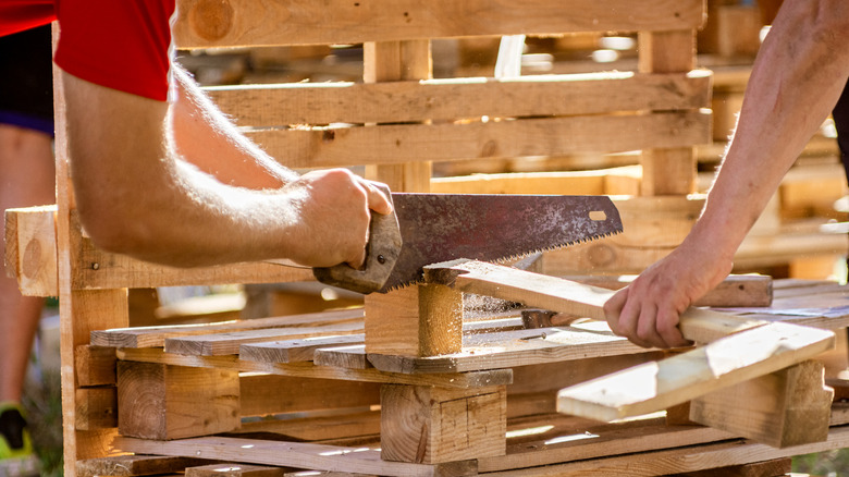 People working together to cut a pallet board