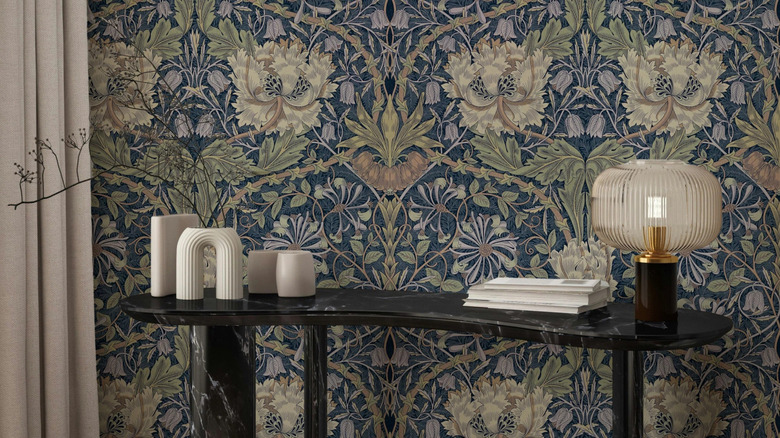 William Morris wallpaper in blue and green next to a side table with candles and a lamp