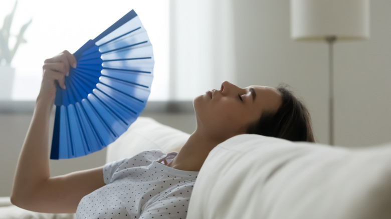 woman fanning herself on sofa