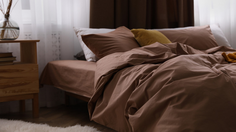 A bed with brown sheets