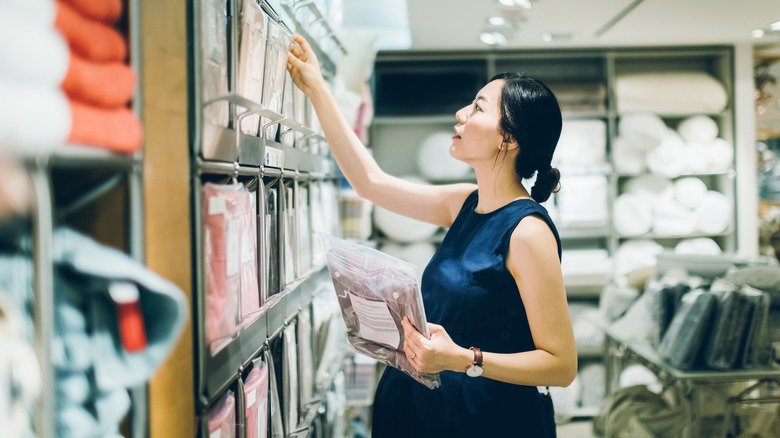 A person shopping for bedsheets in a home decor store