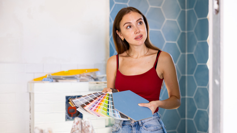 Woman looking at paint samples in a tiled room