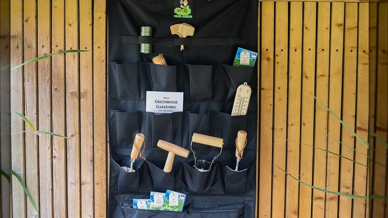 A hanging shoe caddy garden tool organizer with gardening tools inside