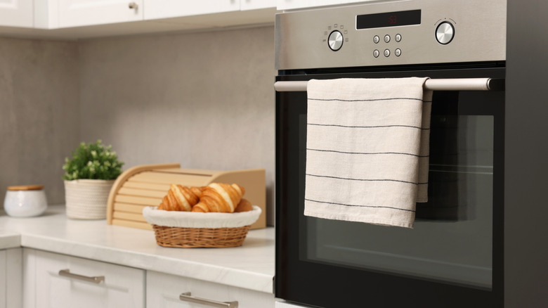 A kitchen towel hanging on oven door in modern kitchen.