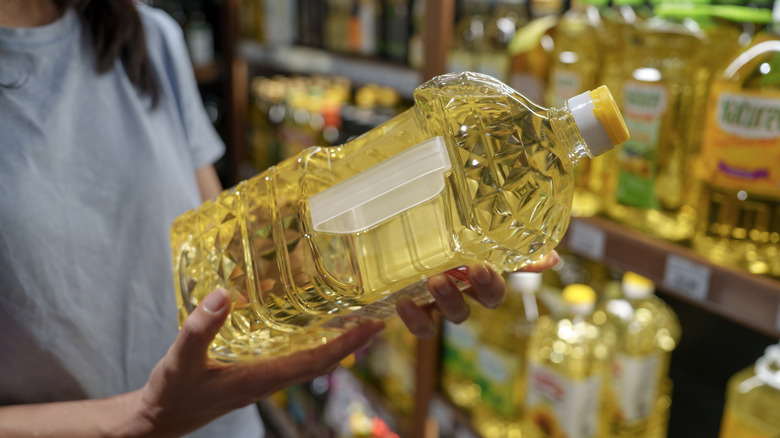 Close-up of a shopper holding a bottle of cooking oil