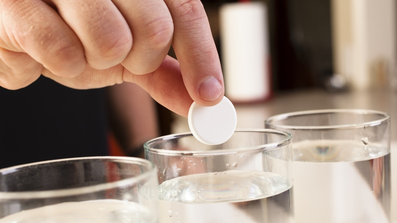 Hand dropping tablet into water