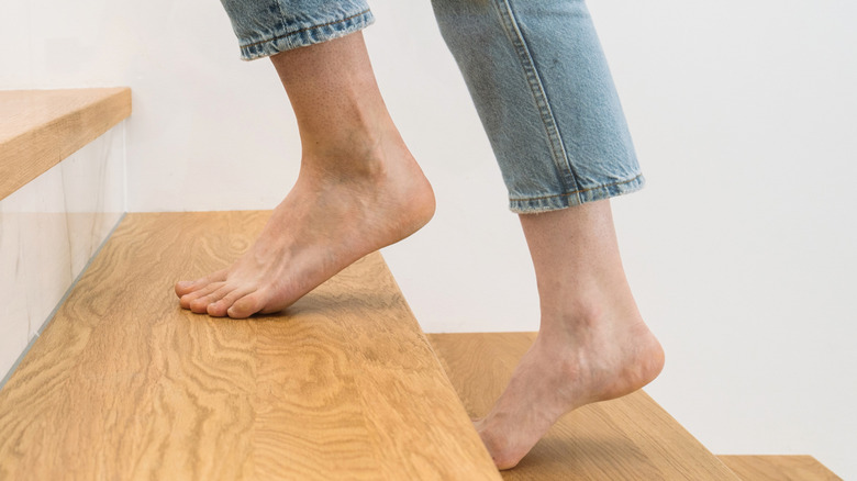 Bare feet walking up a wooden staircase