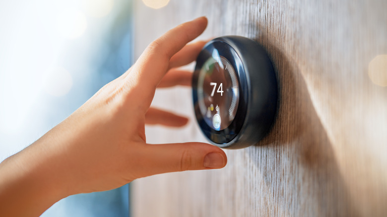 A hand adjusting the temperature on a smart thermostat