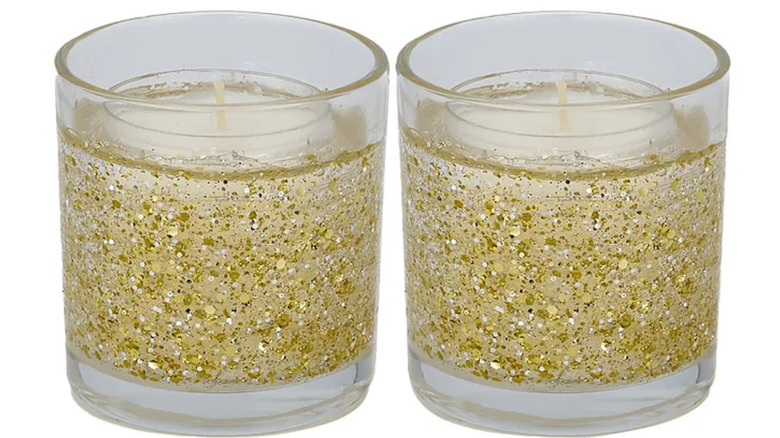 Two white candles in glass holders with a gold glitter finish.