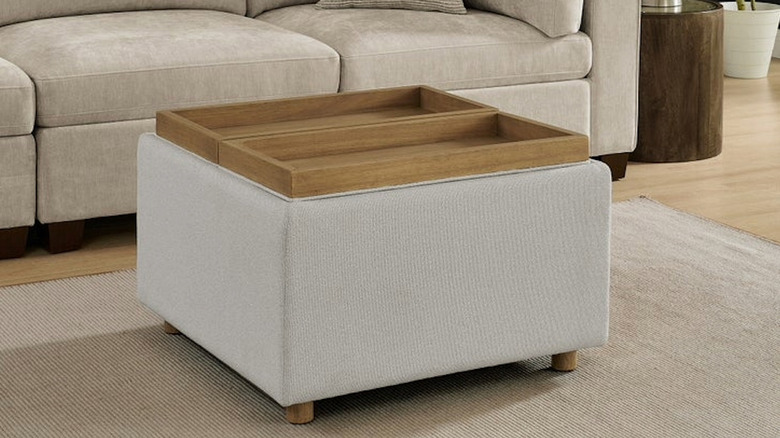 An ottoman with wooden tray tops in front of a couch.