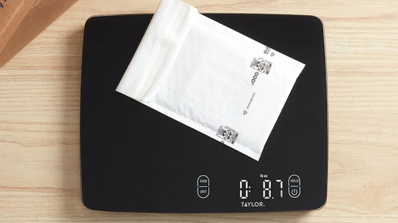 A black kitchen scale on a counter with a packet on the platform.