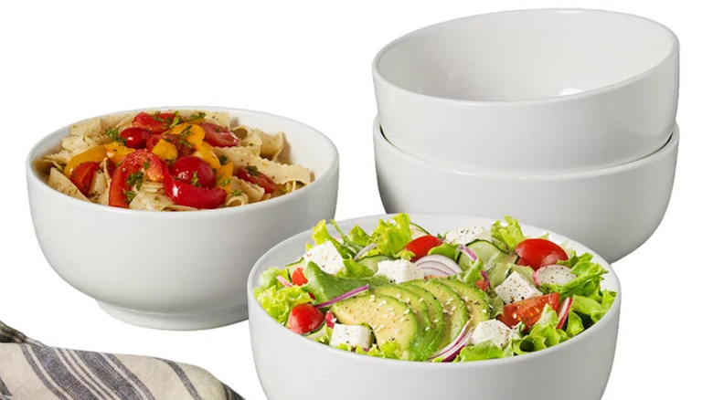 Four white all purpose bowls with two filled with food.