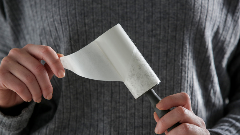 Hand holding a lint roller with fuzz and removing the strip