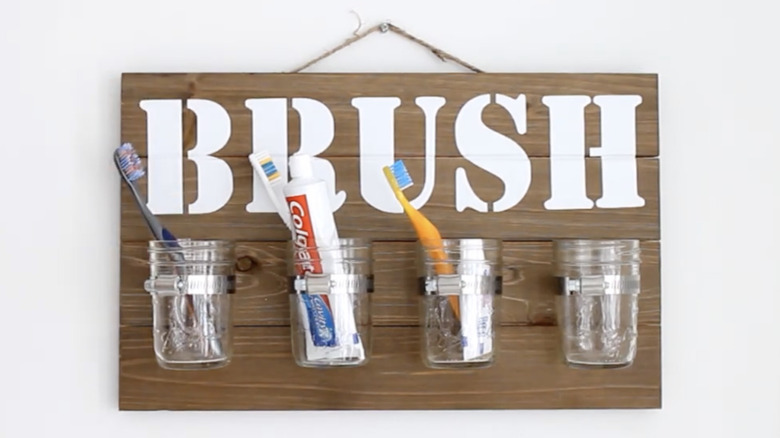 Four glass jars mounted on a piece of wood on a white wall