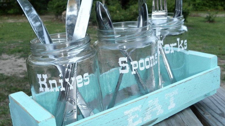 Three pickle jars holding utensils in a teal caddy