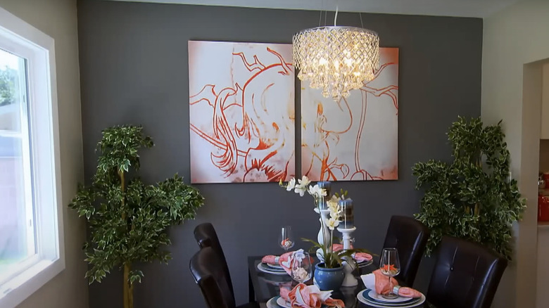 A dark gray wall with art and a chandelier.
