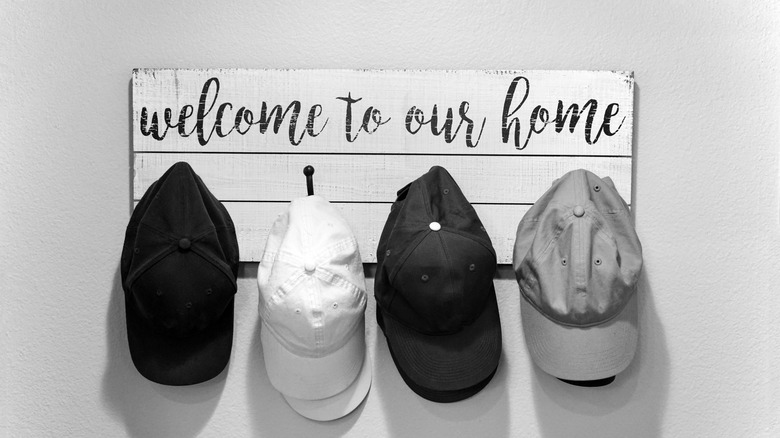Decorative wall sign with hooks holding baseball hats