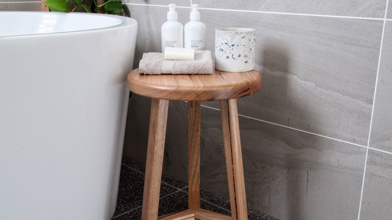 A wooden bathroom stool next to a tub