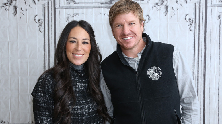Joanna Gaines and Chip Gaines standing in front of a white background