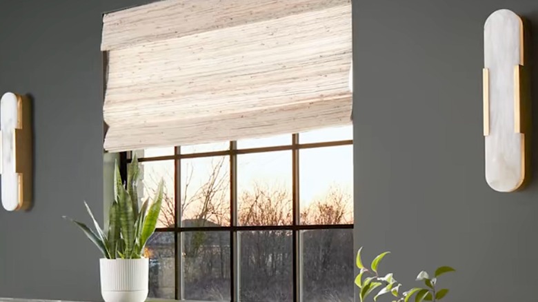 Light-colored Roman shade on an interior window with dark gray walls