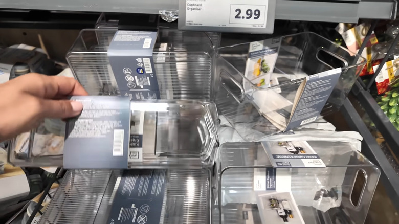Hand holding plastic cupboard organizer in a Lidl