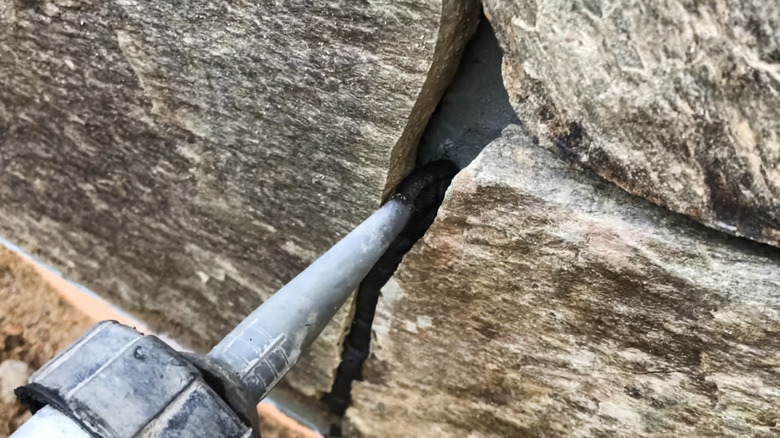 Close up of person filling exterior wall with grout