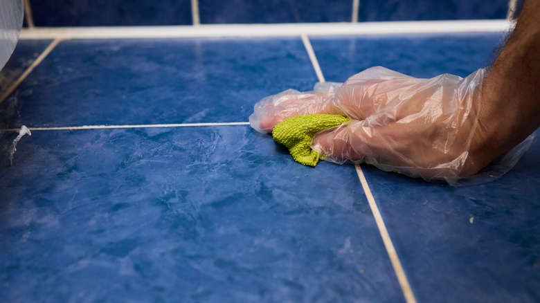 Close up of person cleaning grout between floor tile