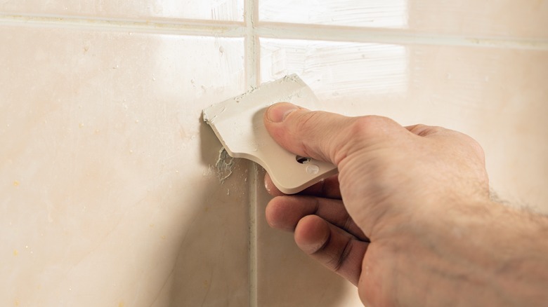 Close up of person installing grout between tile