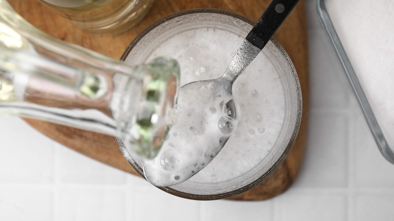 Vinegar being poured into pot of baking soda over a spoon, and frothing
