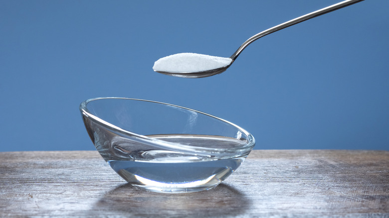 Baking soda on a teaspoon and a cup of clear liquid