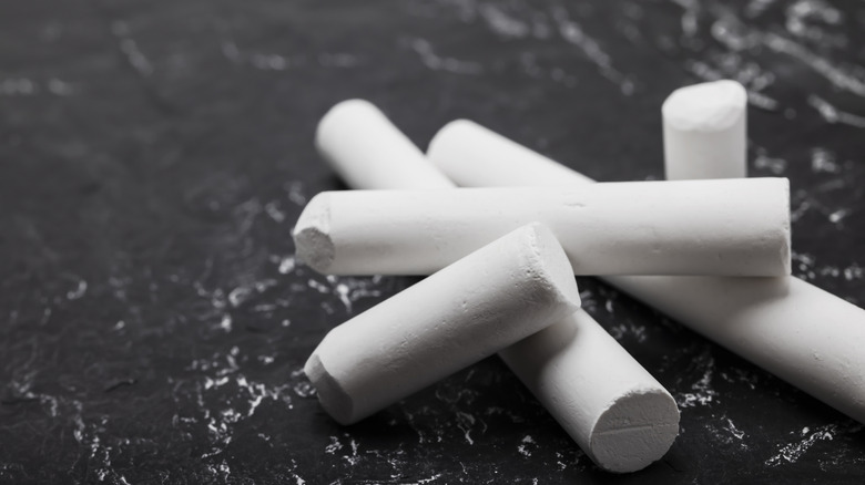 A pile of white chalk on a dark slate background
