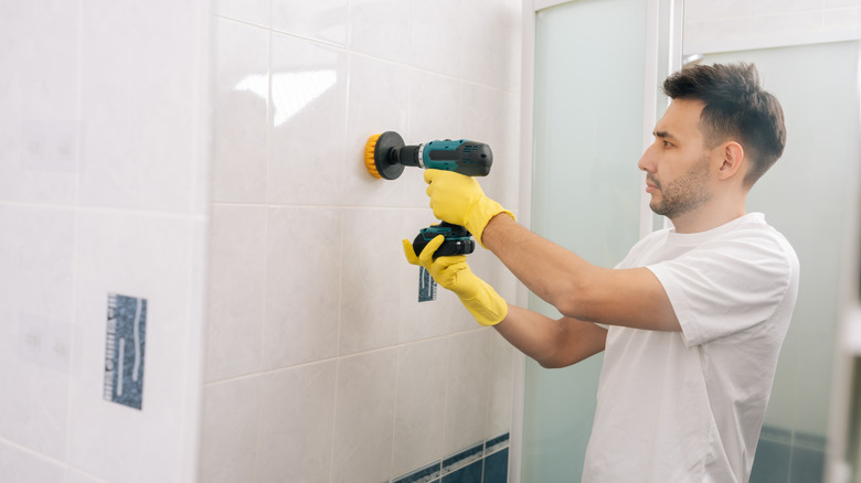 A man cleaning bathroom tiles with a power drill