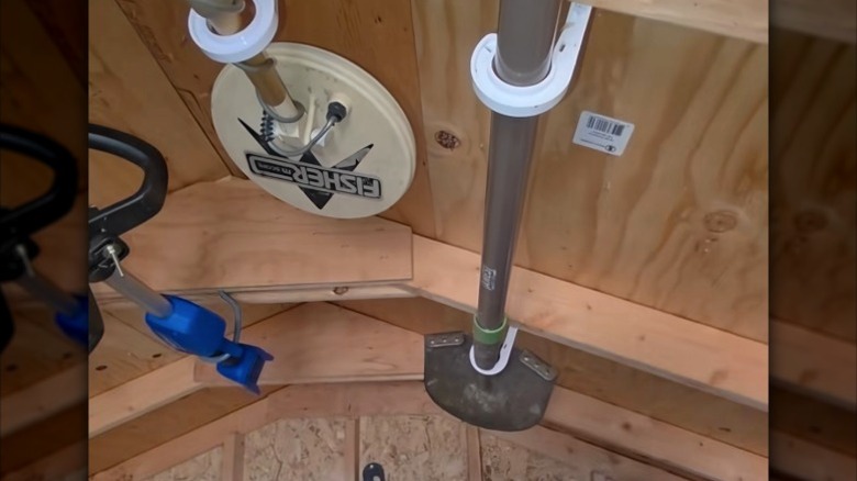 Large hooks in a ceiling holding garden tools