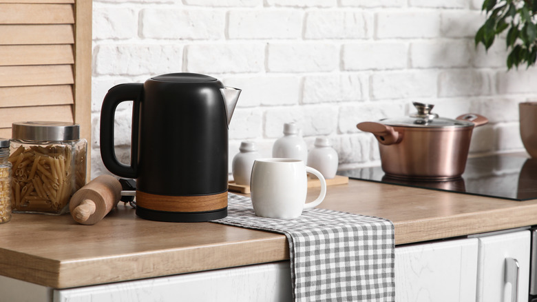 A black tea kettle sitting on a kitchen countertop.