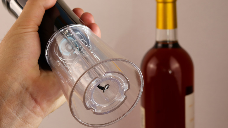 A hand holding an electric wine opener.