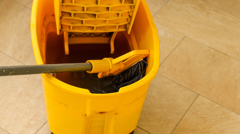 a yellow mop bucket with mop and dirty mop water