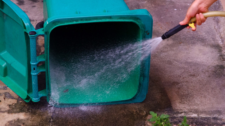 person spraying out the inside of a trash can