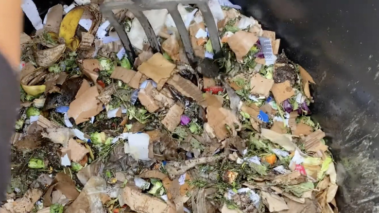 pitch fork mixing cardboard into compost bin
