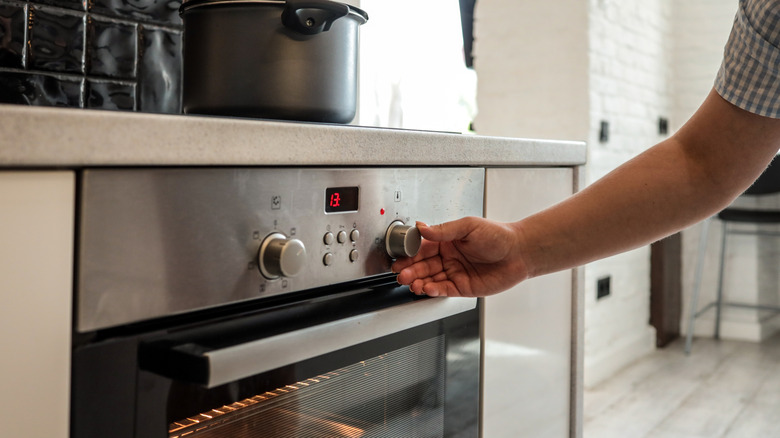 person adjusting oven knob