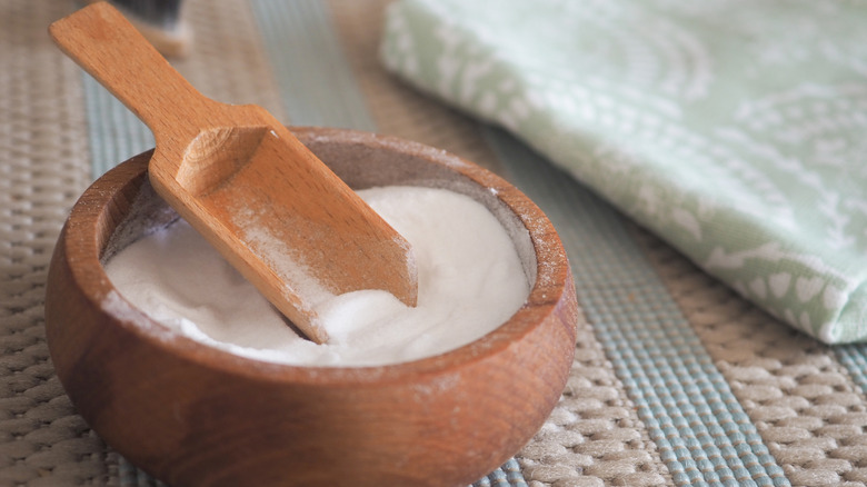 Bowl of baking soda next to towel on carpet
