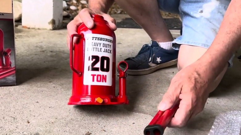 Person holding a 20-ton hydraulic bottle jack