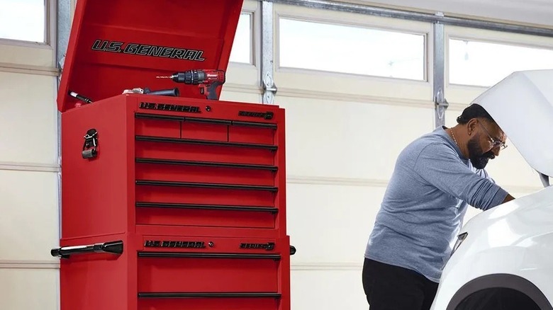 Man working on a car near a rolling tool chest