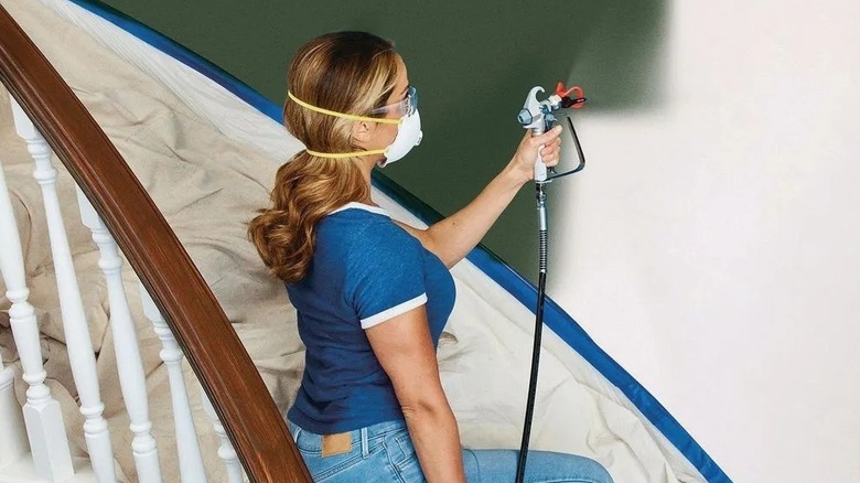 Woman using a paint sprayer on a staircase