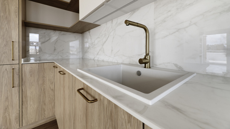 Modern kitchen with white acrylic countertops and gold fixtures