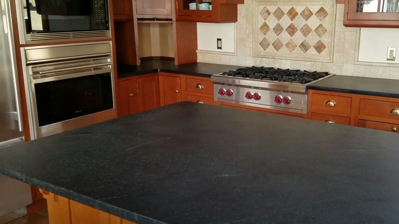 Black soapstone countertop in traditional red wood kitchen