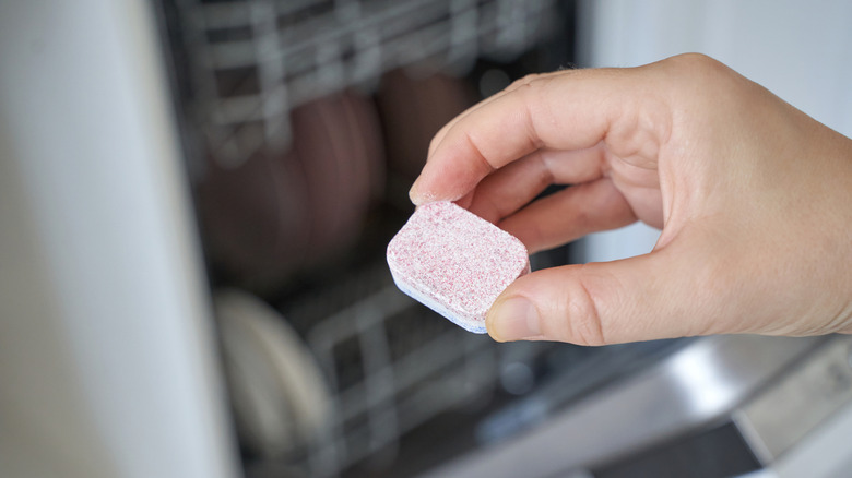 hand holding dishwasher tablet in kitchen