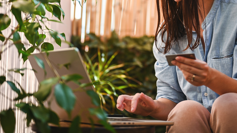 Woman shopping online surrounded by houseplants