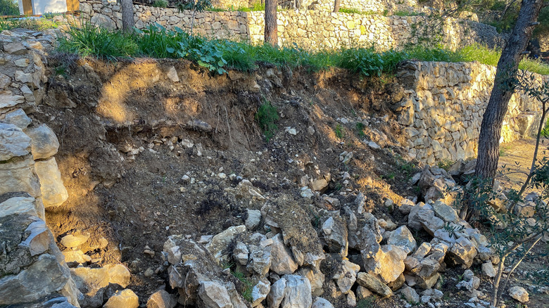 A shot of a retaining wall that has collapsed, revealing the heavy soil behind