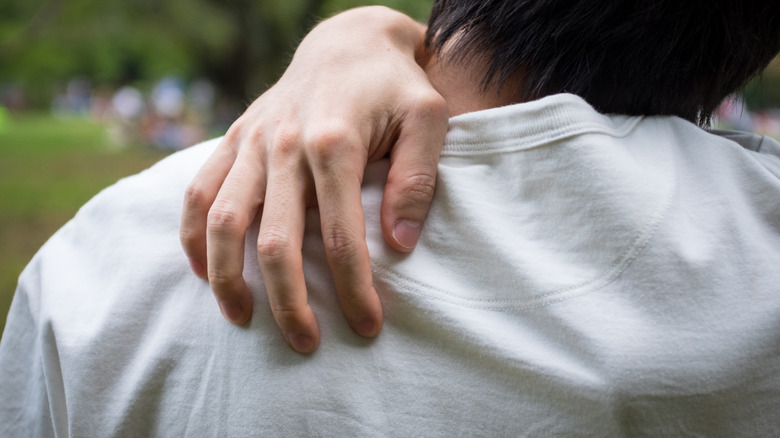 hand scratching over back of shirt